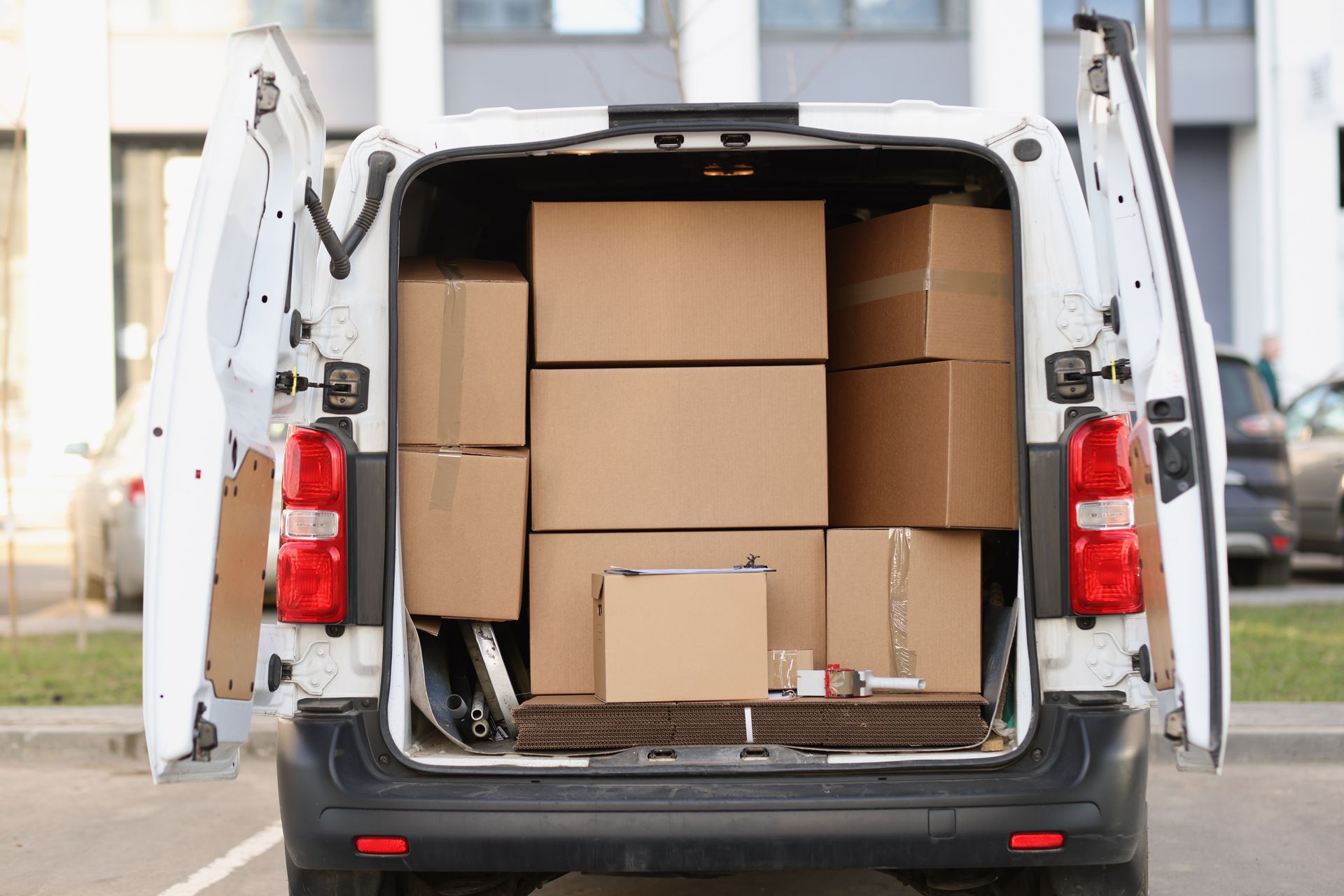 White van with open doors, loaded with several brown cardboard boxes.