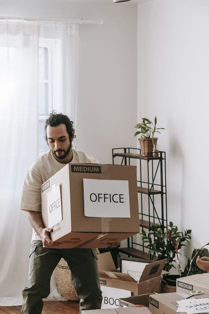 Man carrying a cardboard box labeled 